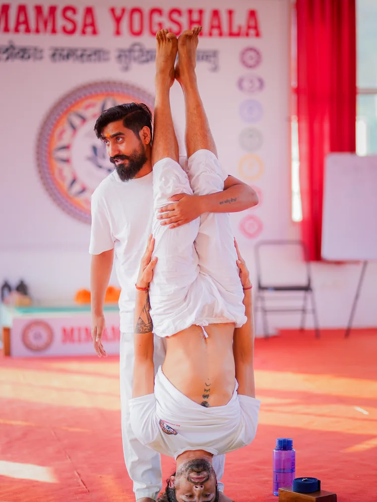 Yogi Manoj spotting a student in Salamba Sarvangasana, supported shoulderstand